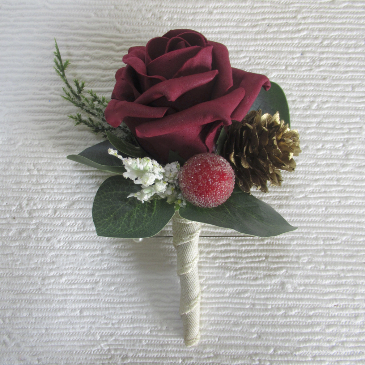 Burgundy rose uttonhole with pine cone, winter inspired buttonholes